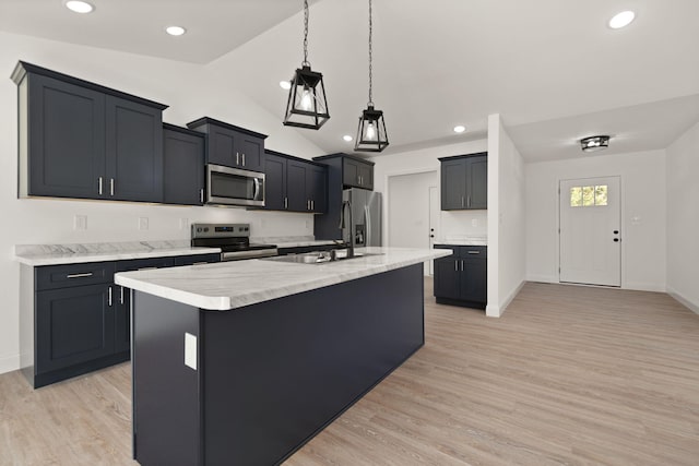 kitchen featuring light hardwood / wood-style floors, appliances with stainless steel finishes, vaulted ceiling, and a center island with sink