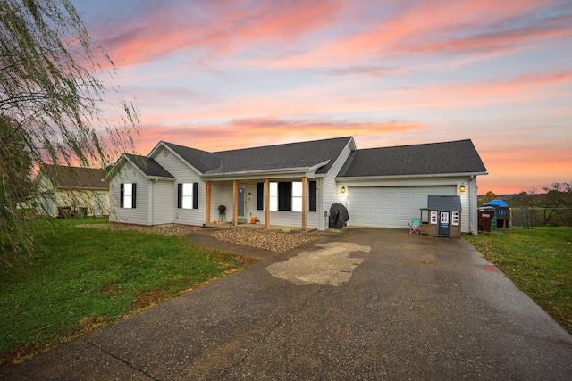 ranch-style home featuring a lawn, covered porch, and a garage