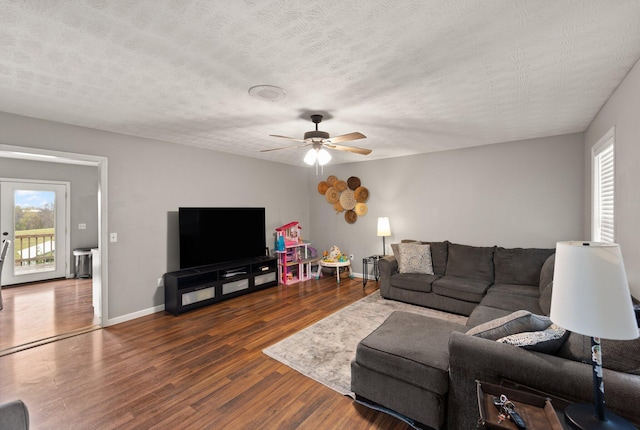 living room with ceiling fan, dark hardwood / wood-style flooring, and a textured ceiling