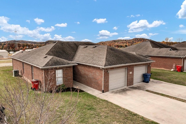 single story home with a front lawn, a garage, a mountain view, and central air condition unit