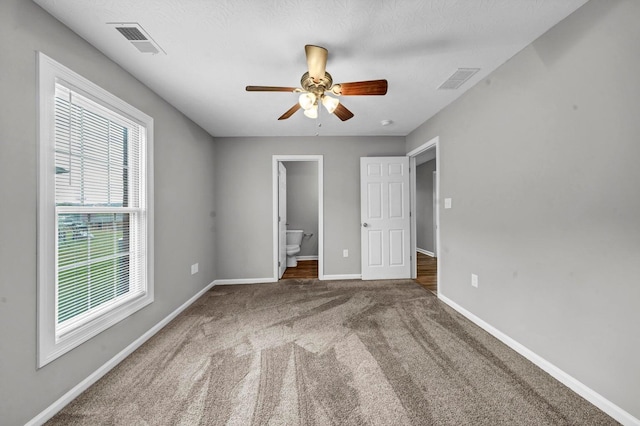 unfurnished bedroom featuring ensuite bathroom, ceiling fan, a textured ceiling, and carpet