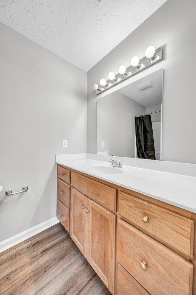 bathroom featuring hardwood / wood-style floors, vanity, and a textured ceiling