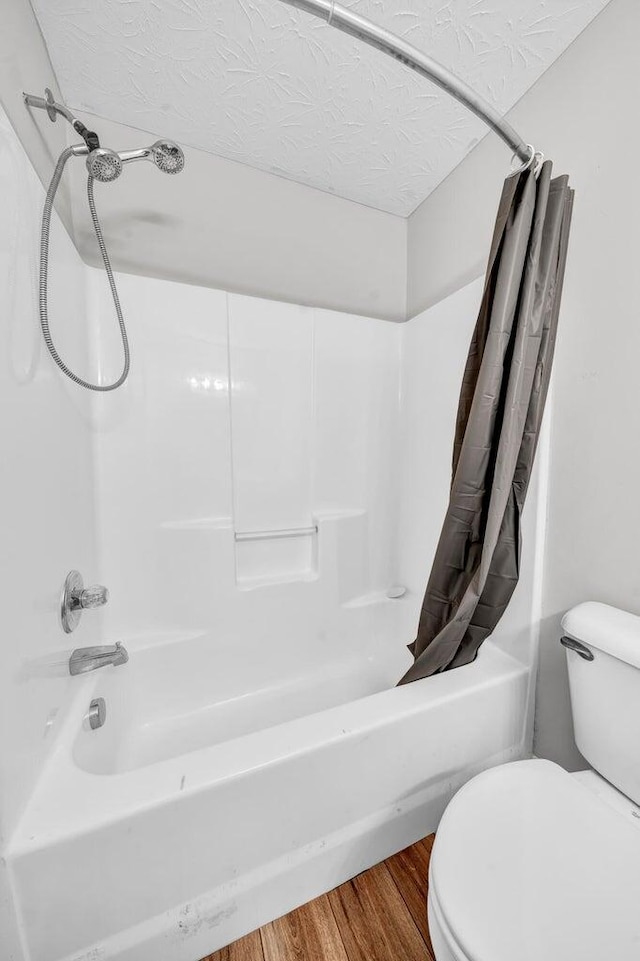 bathroom featuring a textured ceiling, shower / bath combination with curtain, hardwood / wood-style flooring, and toilet