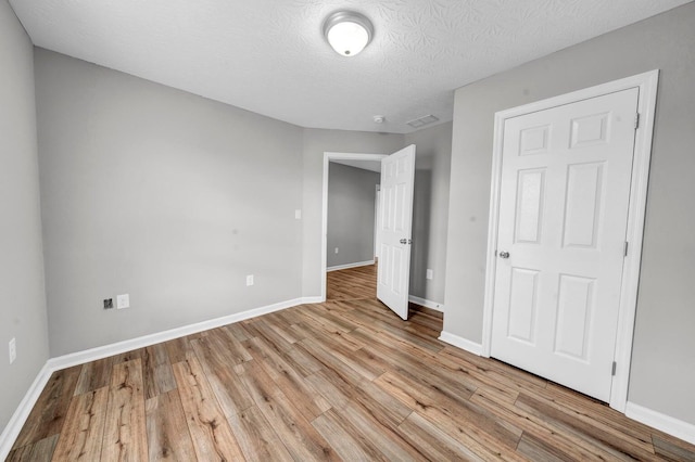 unfurnished bedroom featuring a textured ceiling and light hardwood / wood-style floors