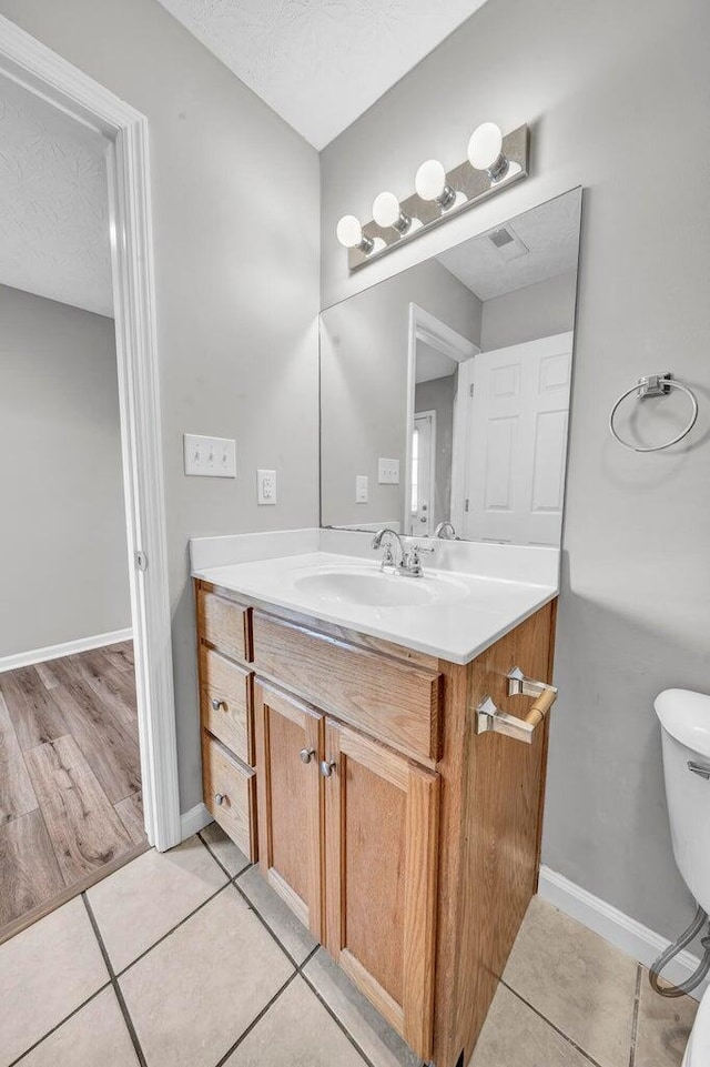 bathroom featuring vanity, tile patterned floors, toilet, and a textured ceiling