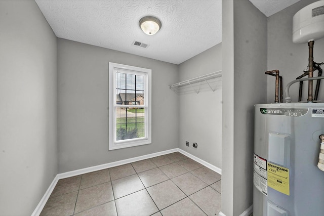 washroom with electric water heater, light tile patterned flooring, a textured ceiling, and electric dryer hookup