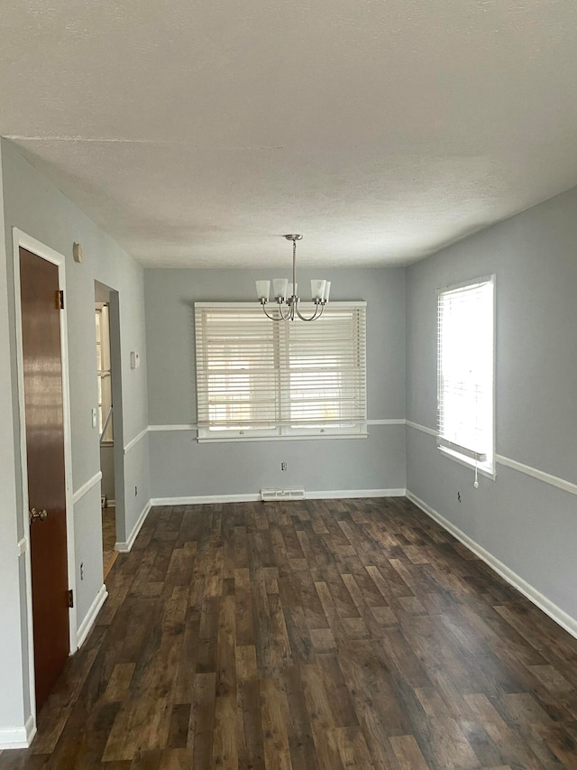 unfurnished room with dark hardwood / wood-style flooring and an inviting chandelier