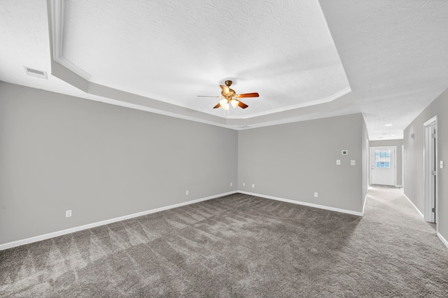 carpeted spare room with ornamental molding, a textured ceiling, ceiling fan, and a raised ceiling