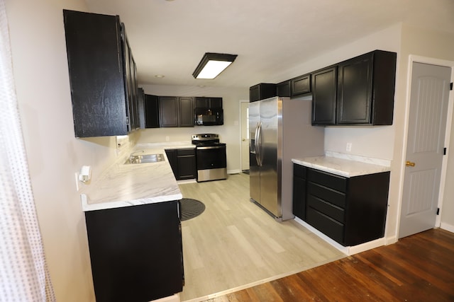 kitchen featuring appliances with stainless steel finishes, sink, and light hardwood / wood-style flooring