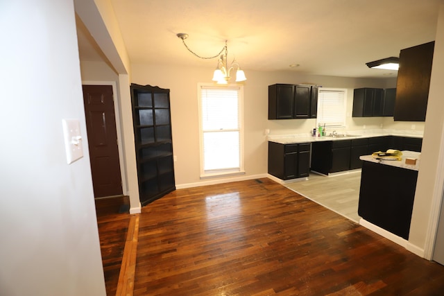 kitchen featuring a notable chandelier, sink, hanging light fixtures, and light wood-type flooring