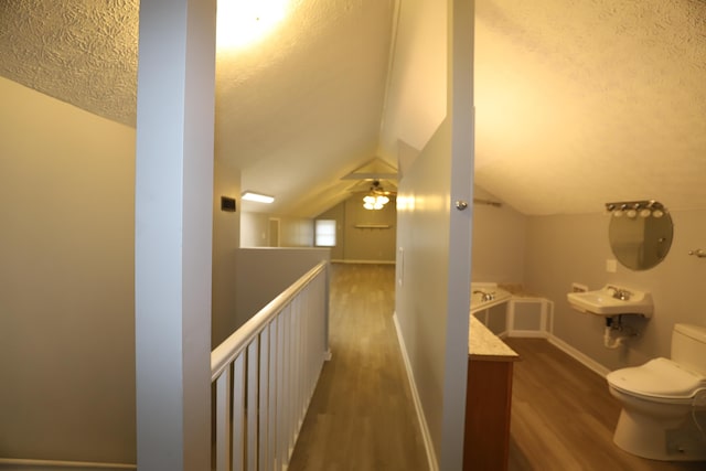 hall with lofted ceiling, sink, a textured ceiling, and dark hardwood / wood-style flooring