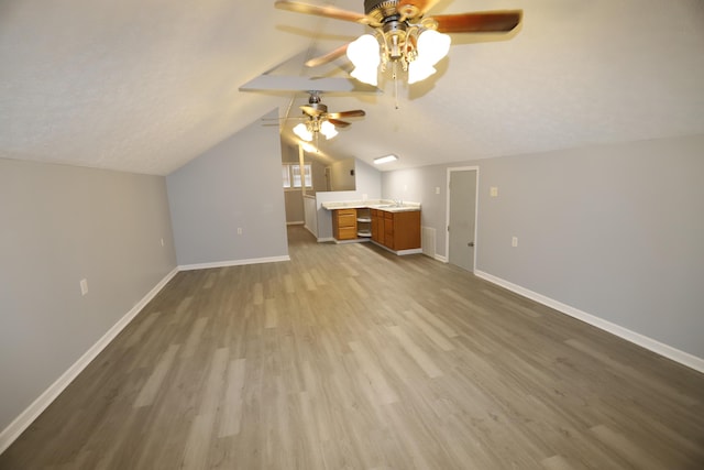 additional living space featuring hardwood / wood-style flooring, ceiling fan, lofted ceiling, and a textured ceiling