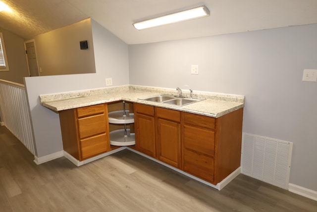 kitchen with sink, kitchen peninsula, and light wood-type flooring