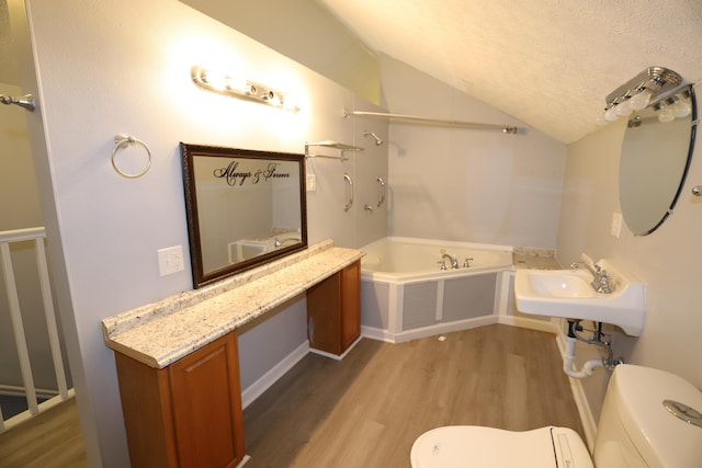 bathroom with a washtub, lofted ceiling, sink, hardwood / wood-style floors, and a textured ceiling