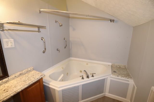 bathroom with vanity, vaulted ceiling, a textured ceiling, and a washtub