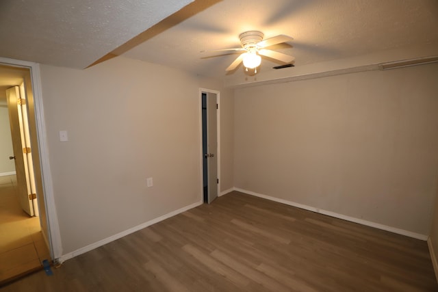 spare room with ceiling fan, dark wood-type flooring, and a textured ceiling