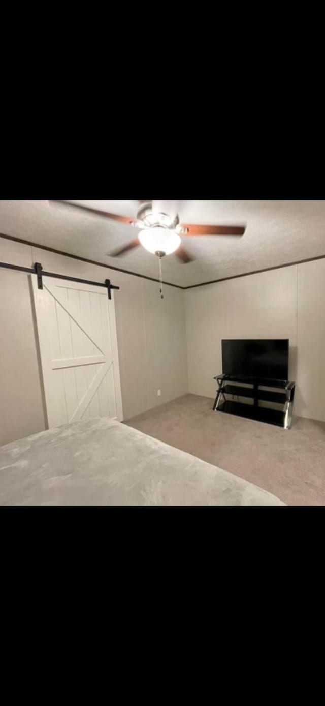 unfurnished bedroom with a barn door and ceiling fan