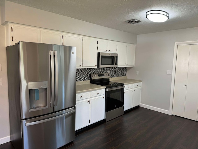 kitchen featuring appliances with stainless steel finishes, a textured ceiling, backsplash, white cabinets, and dark hardwood / wood-style flooring