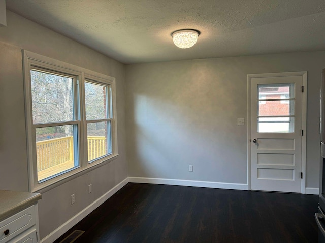 unfurnished dining area with a textured ceiling and dark hardwood / wood-style floors