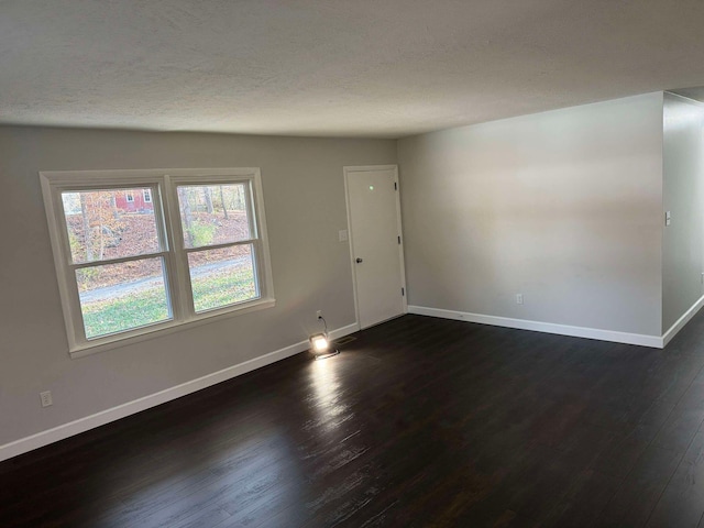 spare room with dark hardwood / wood-style floors and a textured ceiling