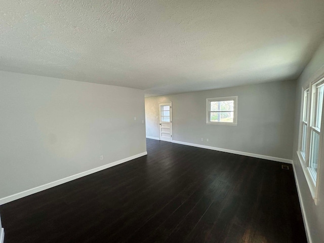 unfurnished room with dark wood-type flooring and a textured ceiling