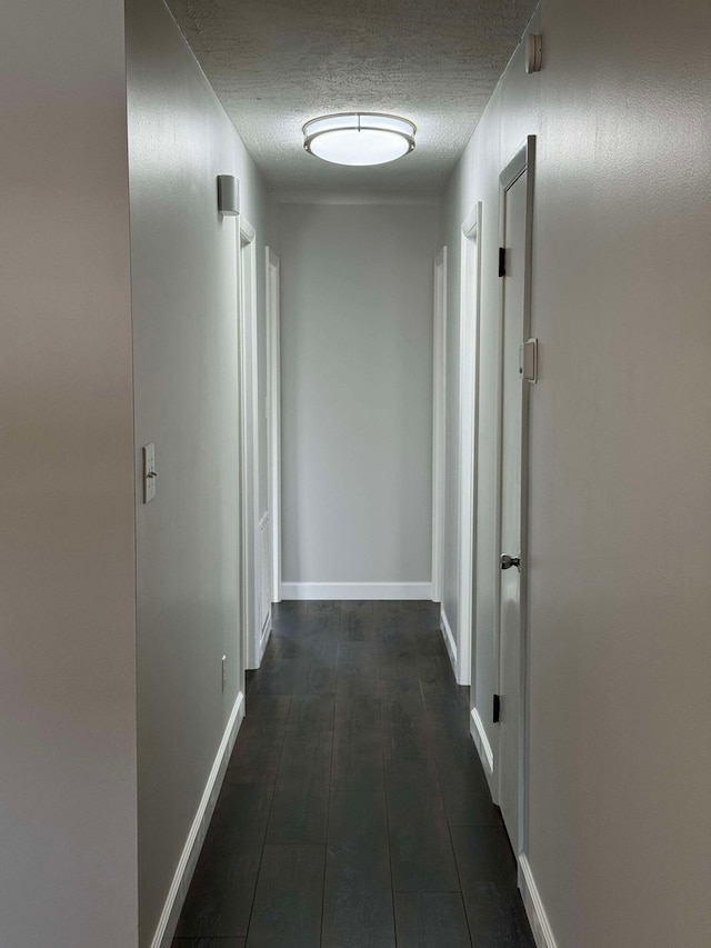 hallway featuring dark wood-type flooring and a textured ceiling