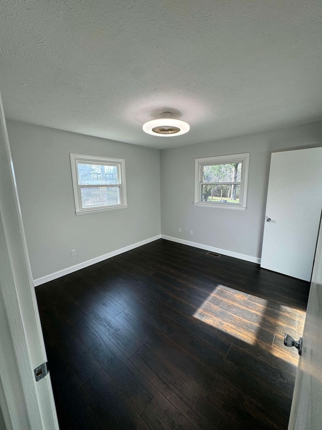 spare room featuring a textured ceiling and dark hardwood / wood-style floors