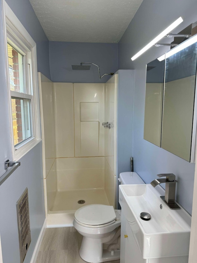 bathroom featuring walk in shower, hardwood / wood-style floors, a textured ceiling, and toilet