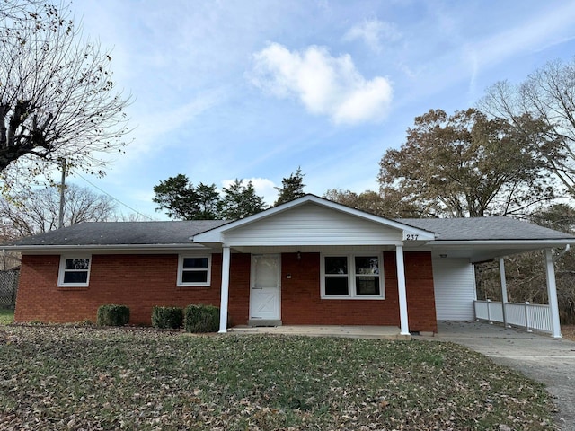 single story home featuring a porch, a carport, and a front yard