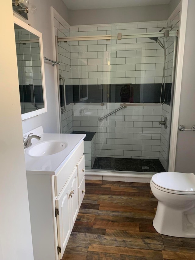 bathroom featuring a shower with door, wood-type flooring, toilet, and vanity