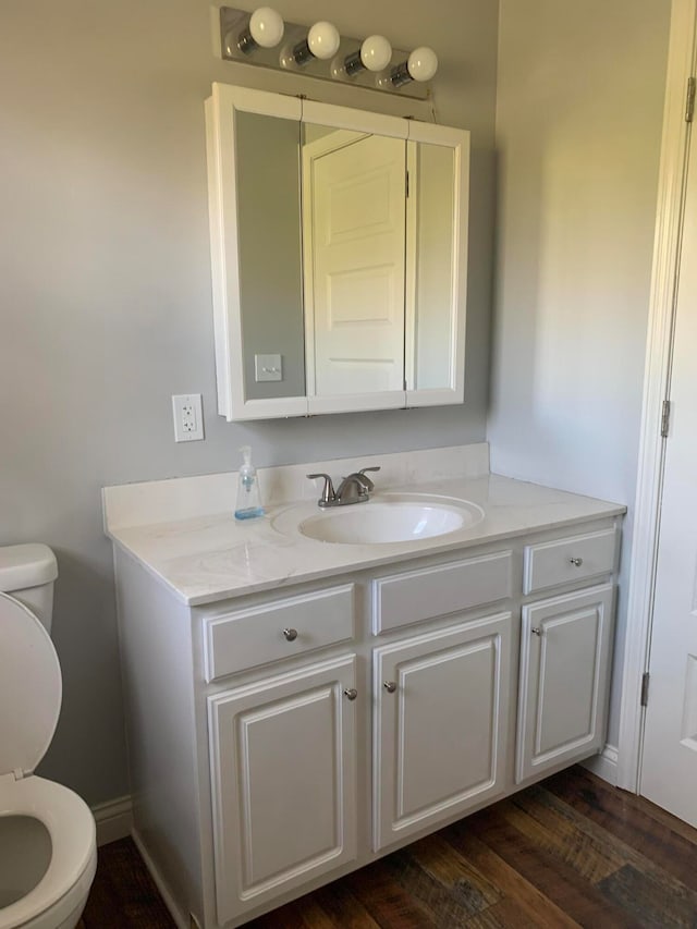 bathroom with toilet, vanity, and wood-type flooring