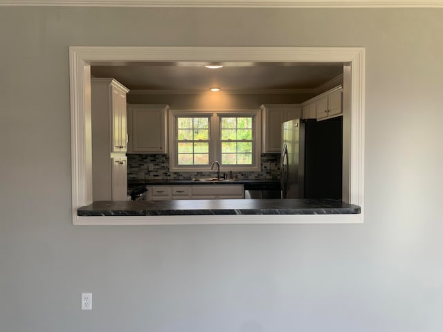 kitchen featuring white cabinets, stainless steel refrigerator, sink, and tasteful backsplash