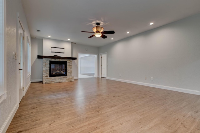 unfurnished living room featuring a stone fireplace, ceiling fan, and light hardwood / wood-style flooring