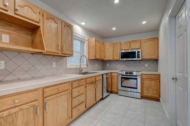 kitchen with tile counters, sink, tasteful backsplash, light tile patterned flooring, and appliances with stainless steel finishes