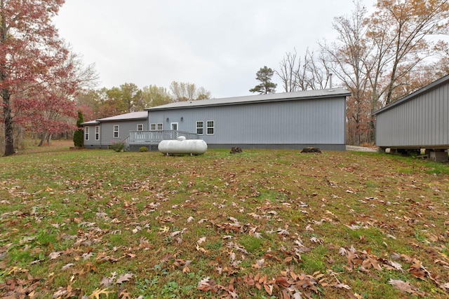 back of property featuring a wooden deck and a lawn