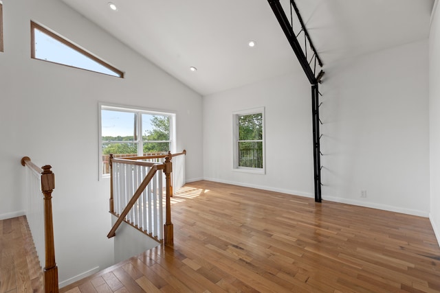 spare room with light wood-type flooring and high vaulted ceiling