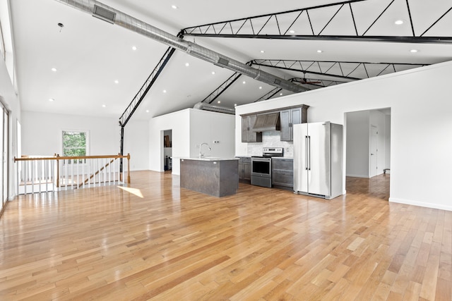 unfurnished living room with light wood-type flooring, high vaulted ceiling, and sink