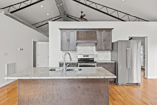 kitchen with light stone countertops, sink, light hardwood / wood-style floors, and appliances with stainless steel finishes