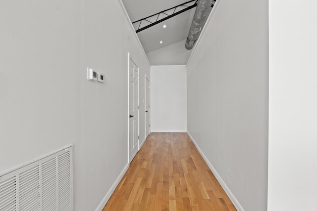 hall with a high ceiling and light hardwood / wood-style flooring