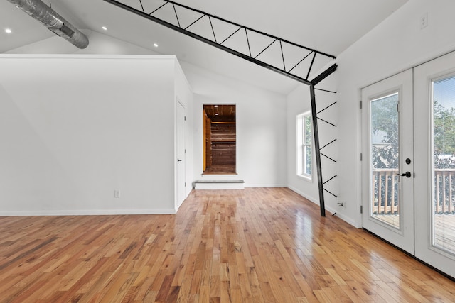 unfurnished living room featuring beamed ceiling, french doors, light hardwood / wood-style flooring, and plenty of natural light