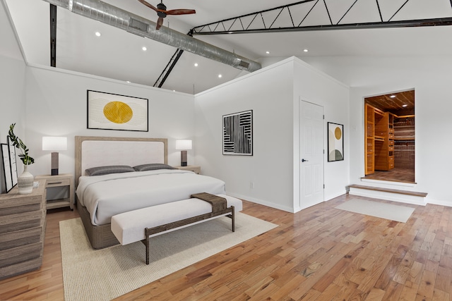 bedroom with ceiling fan, high vaulted ceiling, and light hardwood / wood-style flooring