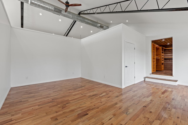 unfurnished living room with ceiling fan, light wood-type flooring, and high vaulted ceiling