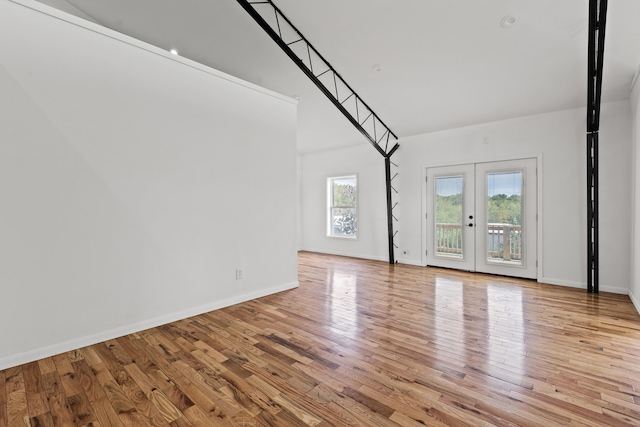 empty room featuring light hardwood / wood-style floors, a towering ceiling, and french doors