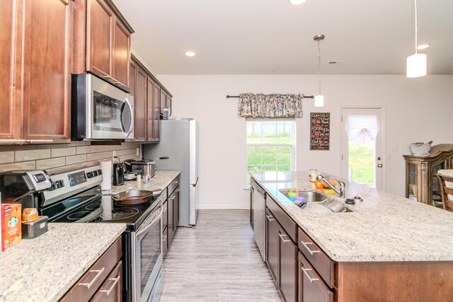 kitchen featuring tasteful backsplash, stainless steel appliances, light stone countertops, sink, and light hardwood / wood-style flooring