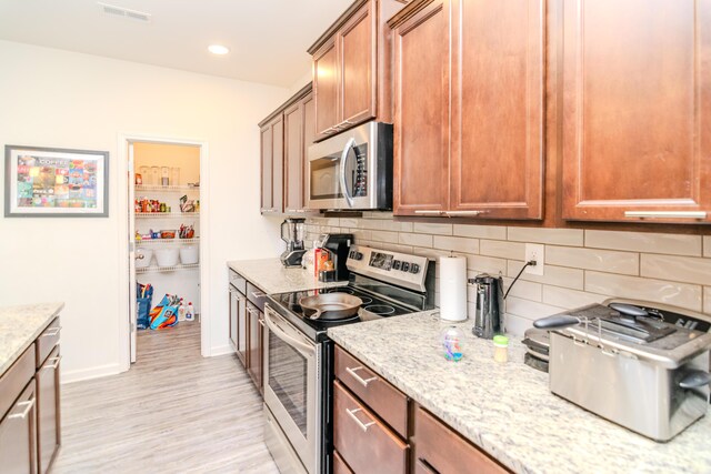 kitchen with dishwasher, hanging light fixtures, sink, an island with sink, and light wood-type flooring