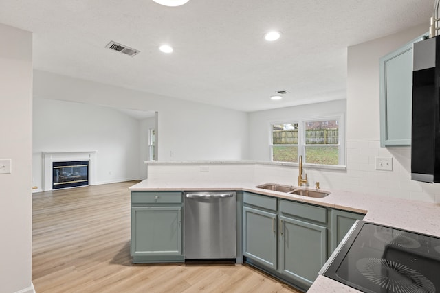 kitchen featuring tasteful backsplash, stove, sink, light hardwood / wood-style floors, and dishwasher