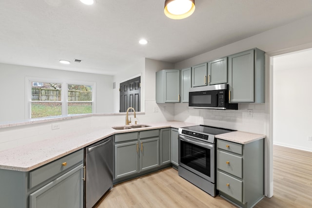 kitchen featuring light hardwood / wood-style floors, sink, appliances with stainless steel finishes, tasteful backsplash, and gray cabinets