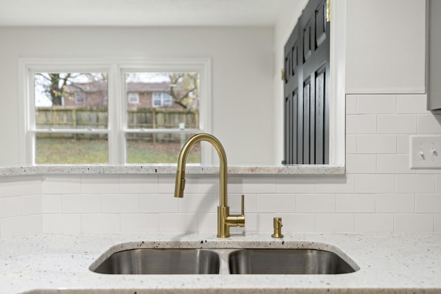 kitchen with tasteful backsplash, sink, and light stone counters