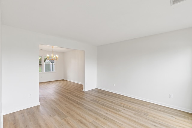 empty room featuring light hardwood / wood-style flooring and a notable chandelier