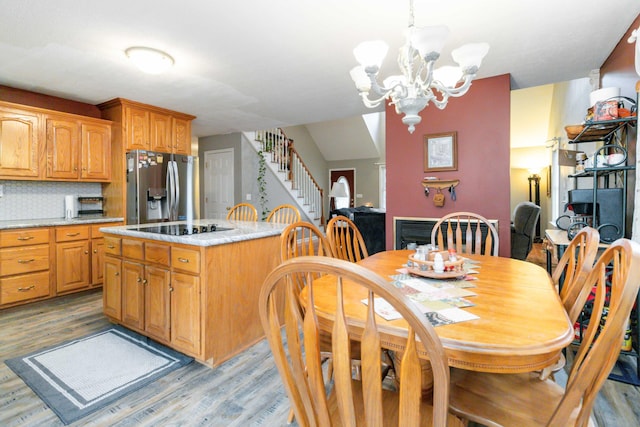 kitchen with light wood-type flooring, stainless steel refrigerator with ice dispenser, and decorative backsplash